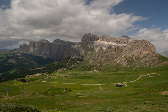 Alpine landscape with rugged dolomite peaks under a bright blue sky and fluffy white clouds, mountains