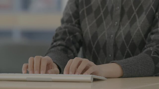 A close-up of a person's hands on a dark keyboard in a tense position suggesting pain or discomfort during extended computer use.