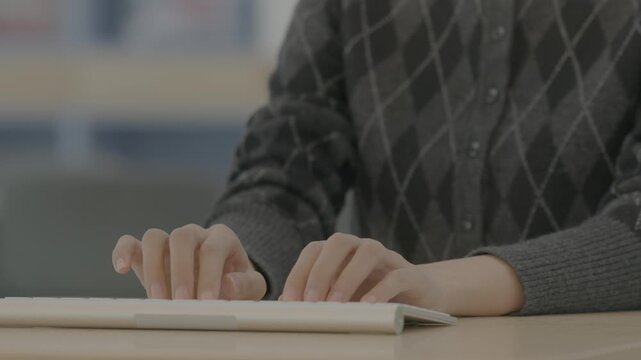 A close-up of a person's hands positioned over a dark keyboard with curved or strained fingers suggesting carpal tunnel symptoms.