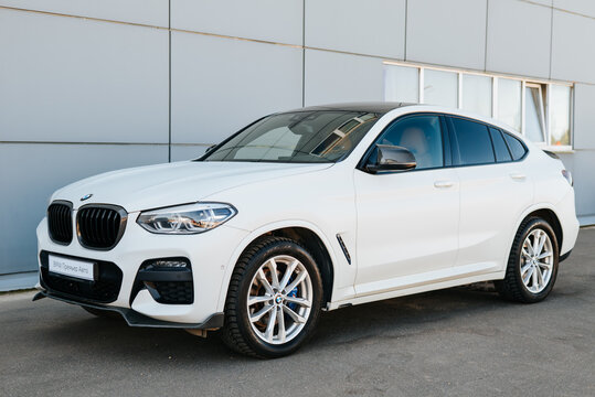 A white BMW X4 is parked near a contemporary building in an urban setting. The scene captures the vehicle's details and design against a backdrop of gray walls Smolensk, Russia 07.17.2026