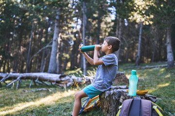 Fototapeta premium Boy drinking water during a forest hiking break