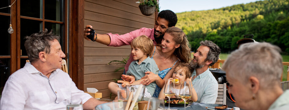 Multigenerational family having bbq party and taking selfie.