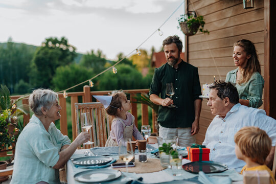 Multi generation family grilling outside on patio in summer during garden party