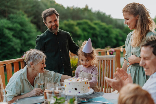 Multi generation family grilling outside on patio in summer during garden party