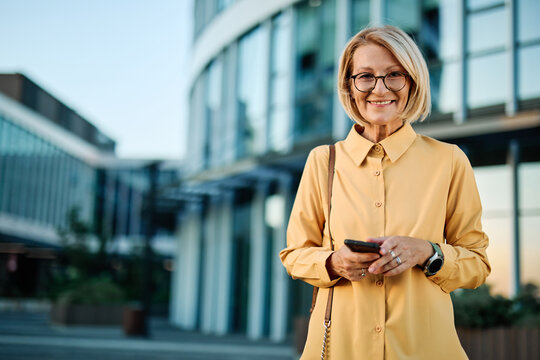 Businesswoman talking on phone with suitcase outdoors