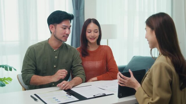 Asian female advisor explain growth budget chart on tablet to young couple in home. Financial investment consultation, insurance plan guidance, house mortgage loan contract, banking strategy concept.