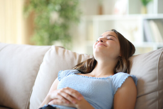 Satisfied teenage girl relaxing and enjoying sitting on a sofa