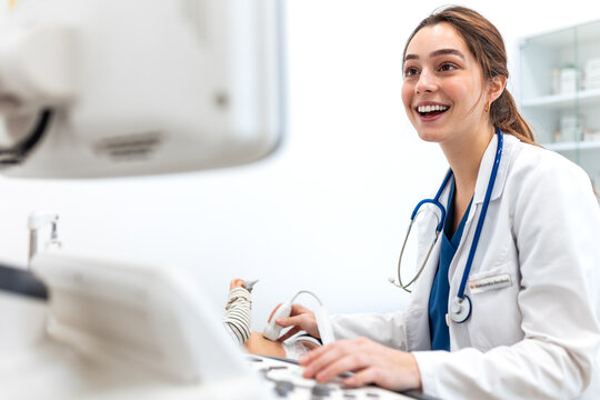 Doctor performing ultrasound scan on baby. Female pediatrician using modern diagnostic medical equipment in clinic. healthcare and pediatrics. Smiling doctor with stethoscope examining infant.