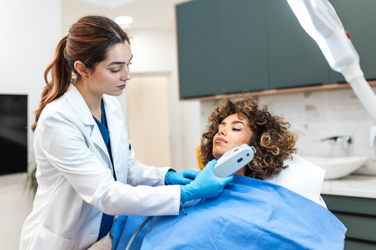 Female doctor performing facial skin treatment. Professional cosmetologist using modern medical device on patient. Beauty, skincare and dermatology concept. Aesthetic procedure in skin clinic.