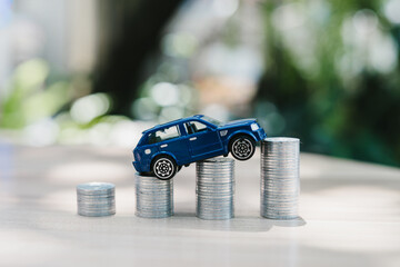 Car finance concept. Toy vehicle climbing coin stacks represents auto loan costs and purchase planning, mobility, budget, payment, growth, ownership
