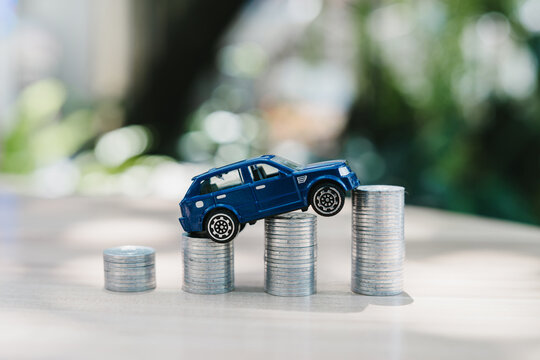 Car finance concept. Toy vehicle climbing coin stacks represents auto loan costs and purchase planning, mobility, budget, payment, growth, ownership