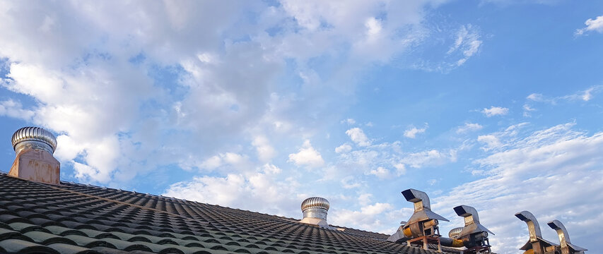 Stainless steel roof ventilator spin on tile roof with blue sky. Roof exhaust ventilation fan ball on factory or house roof, Air ventilator mechanism installed. not ai