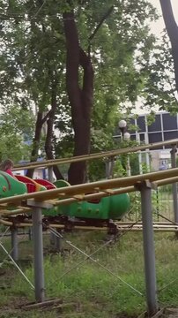 Young child having fun on a colorful caterpillar shaped roller coaster in an old amusement park