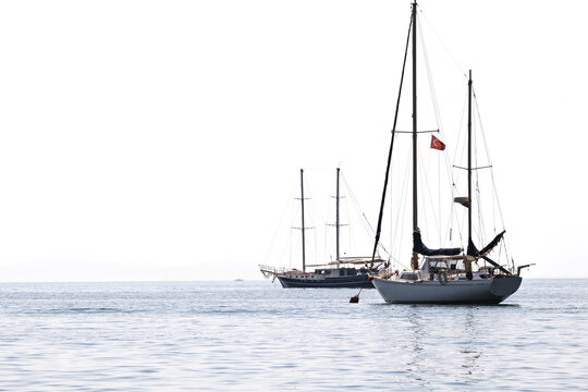 Sailboats lay at anchor offshore. Luxury yacht concept. Boats aligned to the right for the text area on sea or ocean. Ships or marine vessels. Copy space, blank, empty. No people, nobody. Horizontal p