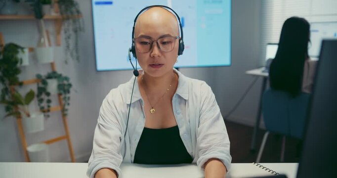 Young Asian female agent talking on phone headset consulting client online in call center office. Corporate customer service, technical support, remote tech operator, business team help desk concept.