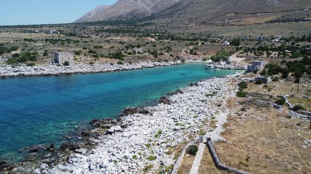 Drone footage of the secluded Gialia Bay on the Mani Peninsula, Greece, featuring turquoise Mediterranean waters, a rocky coastline, and an authentic coastal landscape.