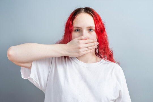 Young woman covering her mouth with hand as a metaphor for silence, self censorship and fear of speaking up. Mental health, anxiety, emotional suppression and communication block concept.