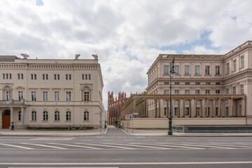 Fototapeta premium Historic palaces and a classical colonnade frame a quiet side street near Bebelplatz. Road markings and a decorative lamp define the Berlin city scene.