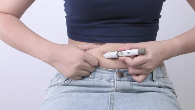 Focused woman prepares glp1 injection in stomach using medical pen for diabetes weight loss treatment during home daily health routine