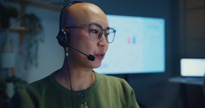Close up young Asian businesswoman working late talk on telephone headset in call center office at night. Corporate customer service support, telemarketing agent, finance insurance investment advisor.