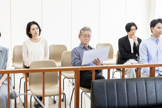 法廷の傍聴席で風刺絵を描きながら裁判を見守る男性