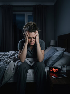 Caucasian woman sufferer sitting on bed holding head in pain at night with digital clock showing three AM. Sleep disorder and mental health awareness vertical banner
