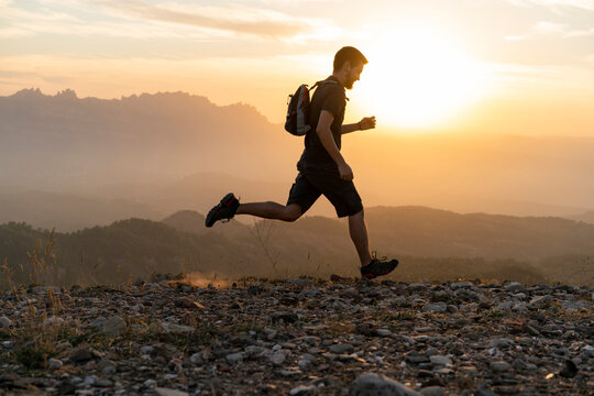 Spain, Barcelona, Natural Park of Sant Llorenc, man running in the mountains at sunset