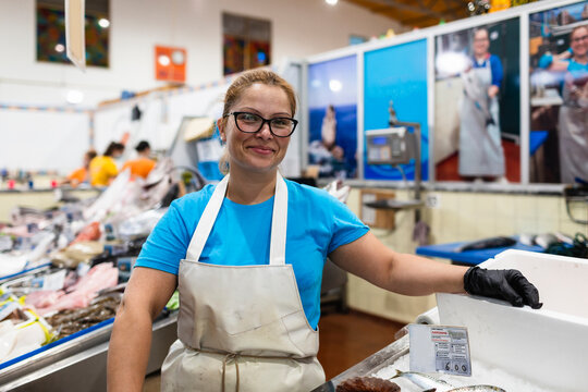 Smiling fishmonger standing at indoor market counter