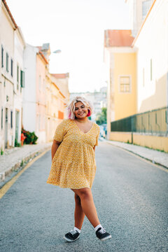 Smiling plus size woman standing with crossed leg on road