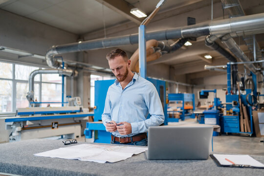 Portrait of carpenter examining documents in production hall