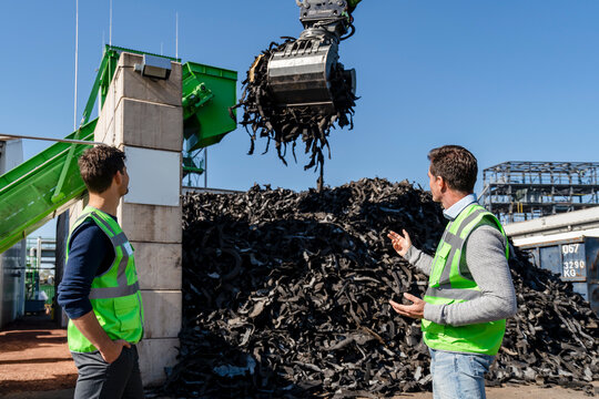 Man discussing over excavator with colleague at recycling center