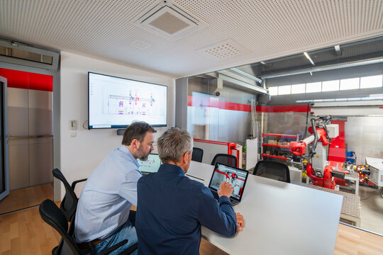 Male engineer programs an industrial robot in a modern office