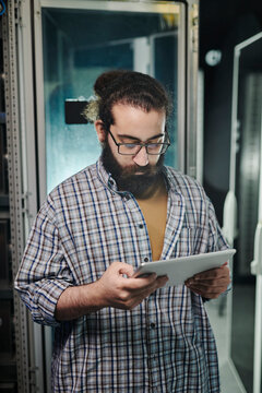 Young technician working on tablet PC in server room