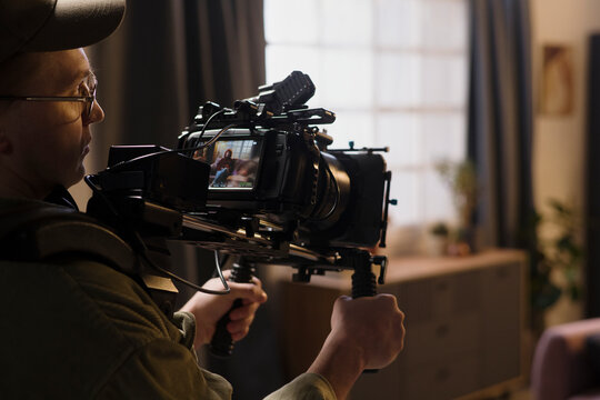 Male cameraman films a woman indoors on a professional movie set