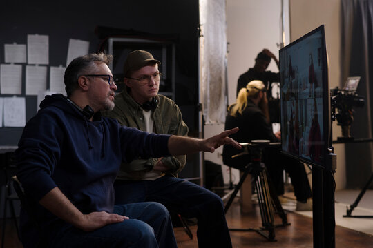 Director and crew member review video playback on a studio monitor