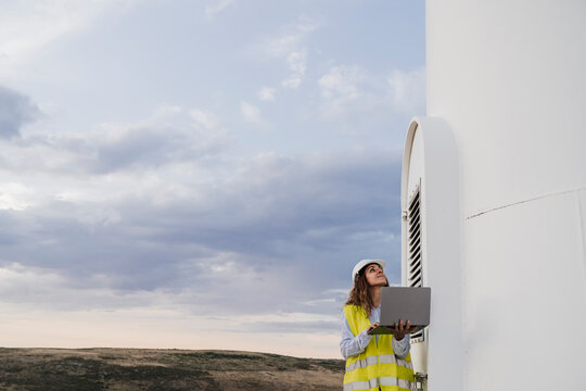 Engineer working on laptop near wind turbine