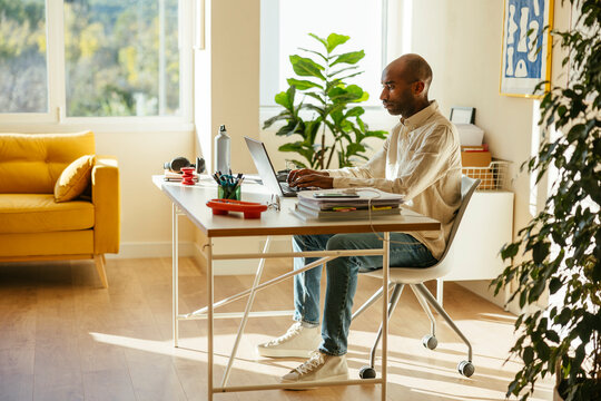 Determined businessman working remotely through laptop at home office