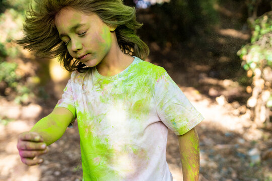 Boy shaking his head, full of colorful powder paint, celebrating Holi, Festival of Colors