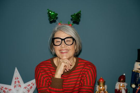 Smiling mature woman wears a Christmas headband indoors