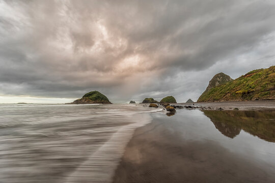 New Zealand, Tongaporutu, Cloudy sky over sandy coastal beach at dusk with Motuotamatea island in background