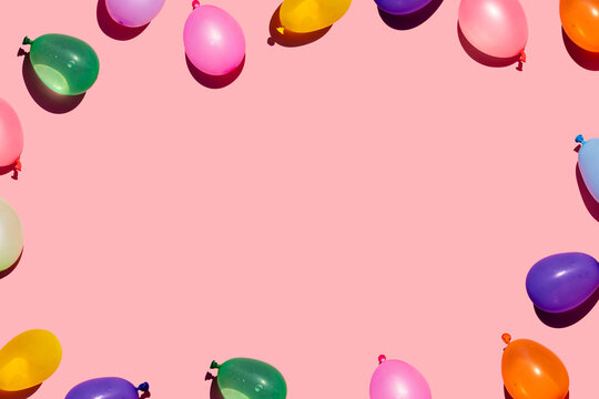 Studio shot of pink empty background surrounded by colorful water balloons