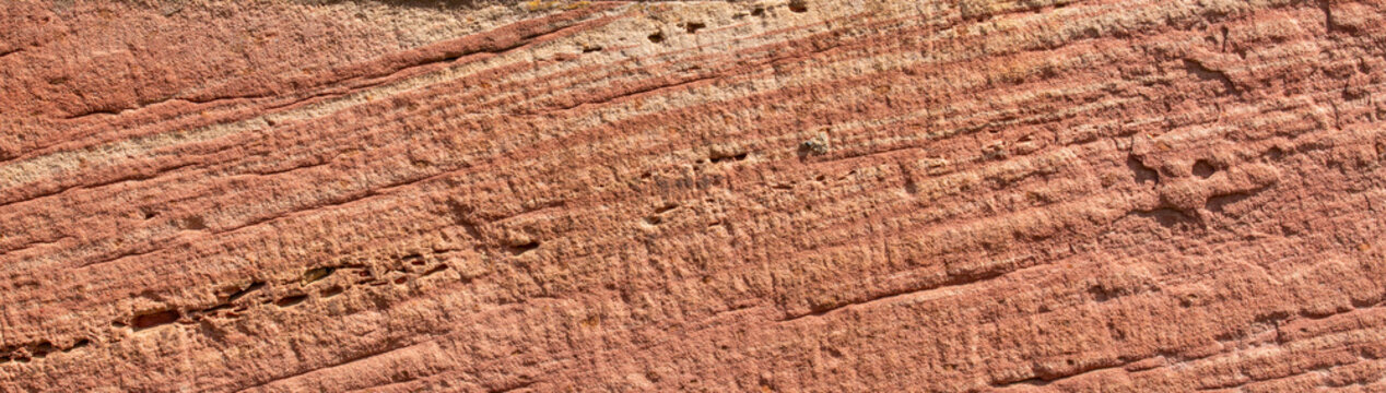 Rough textured red sandstone wall background with layered diagonal lines and small holes