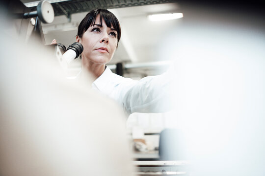 Female technician with microscope at industry