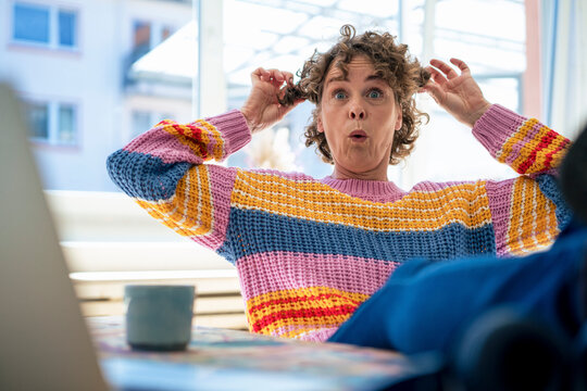 Mature woman holding hair making face at home