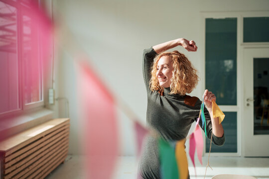 Happy businesswoman decorating office with bunting