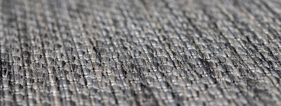 Grey woven fabric textile material surface texture background with shallow depth