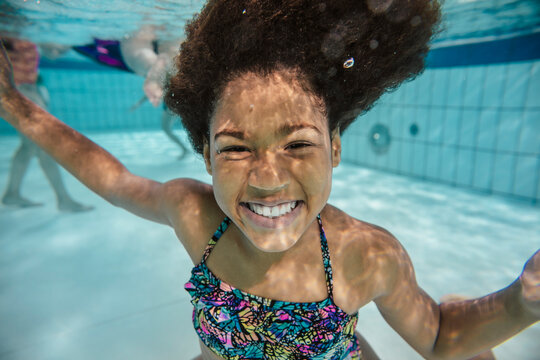 Portrait of smiling girl under water in swimming pool
