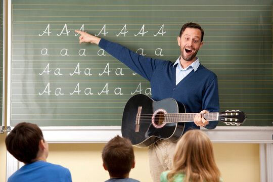 Teacher with guitar at blackboard showing variations of letter A