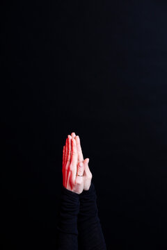 Hand gesture of praying with red light on black background