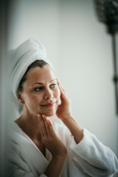 Woman checking skin looking in mirror at home